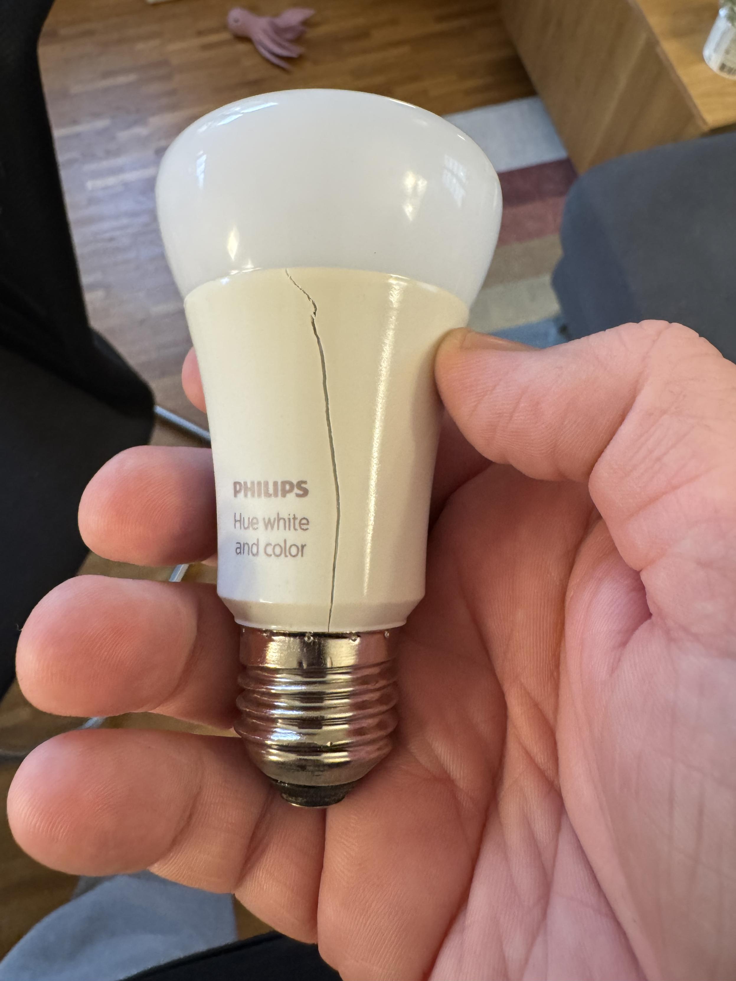 Eine smarte Glühbirne von Philips Hue. Der Lampenkörper aus weißem Kunststoff hat einen deutlich sichtbaren Riss über die ganze Länge.